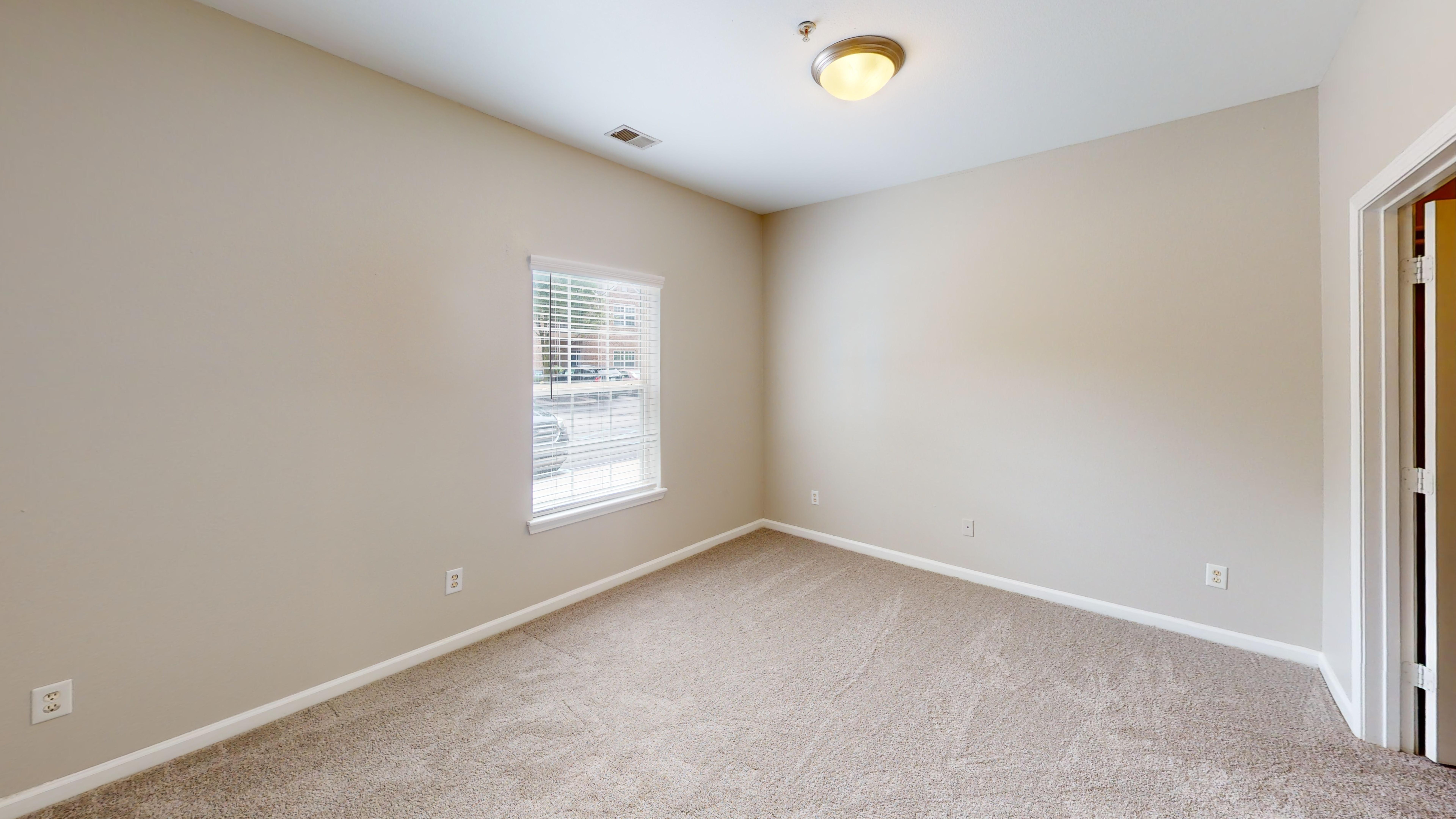 Secondary bedroom with window and carpet